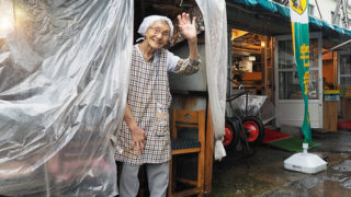 はるえ食堂の前で手を振るはるえさん